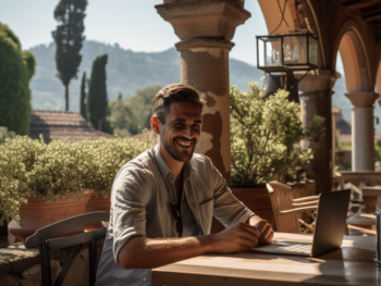 clean shaven smiling expat working at laptop Italian